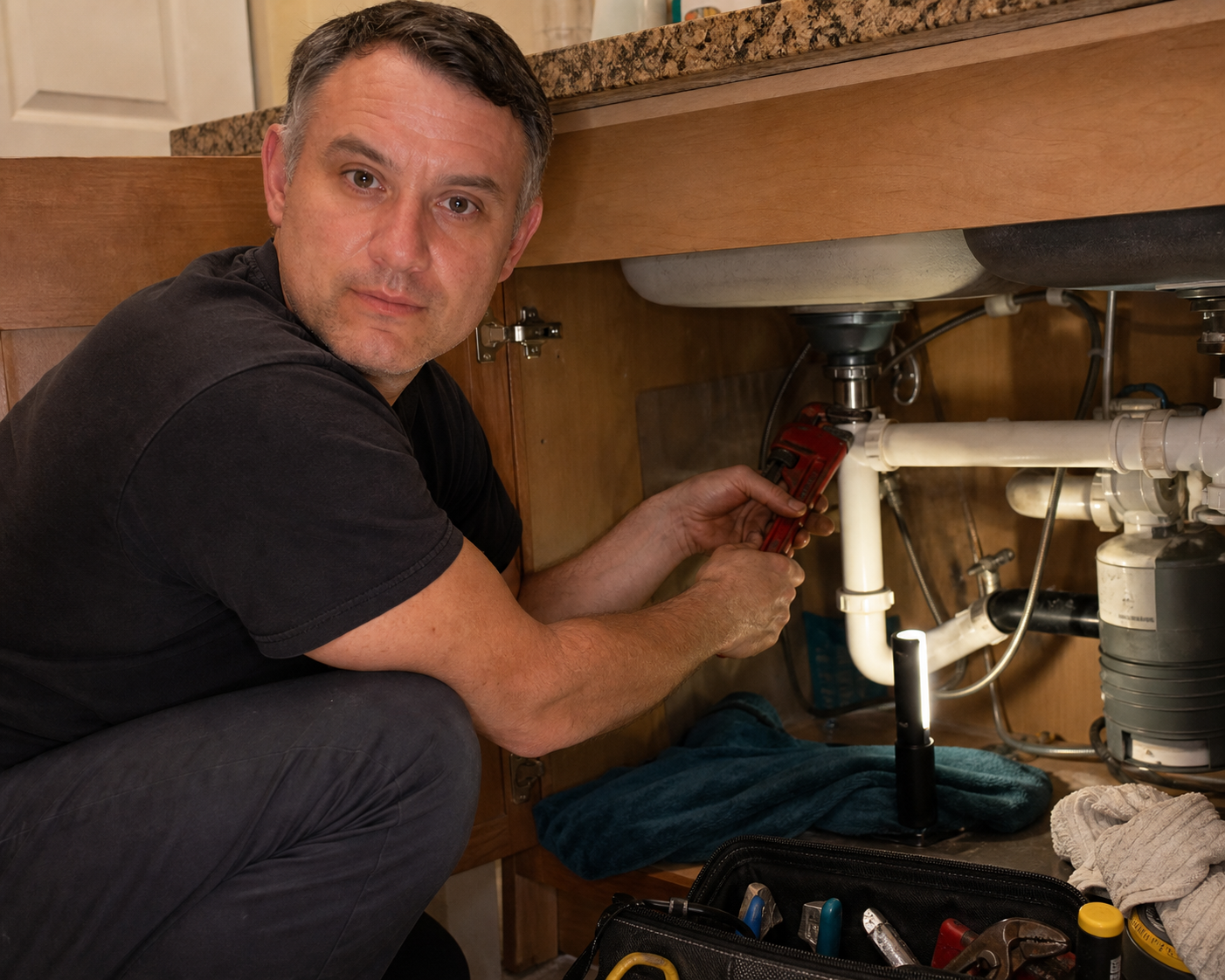 Harry doing indoor plumbing repair under a sink